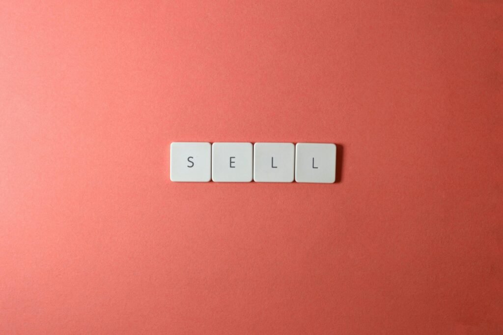 Close-up of keyboard tiles spelling 'sell' on a red background, minimalist design.